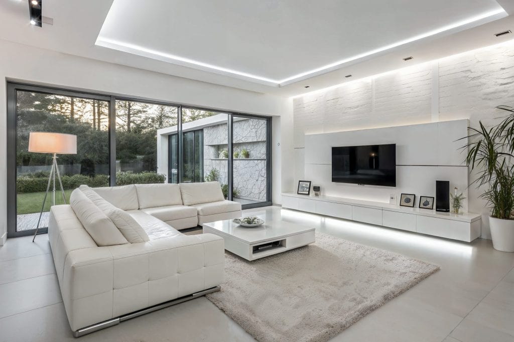 Layered lighting adding visual depth to an all-white living room by Decorilla